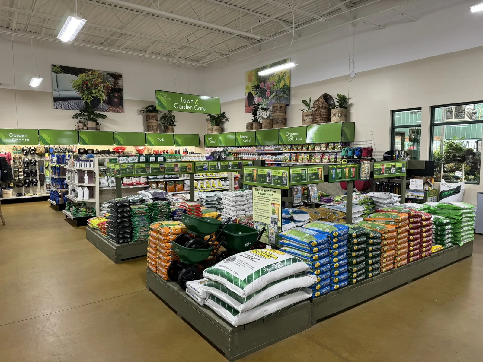 Interior of a garden center with organized shelves of lawn care products, fertilizers, tools, and garden supplies.