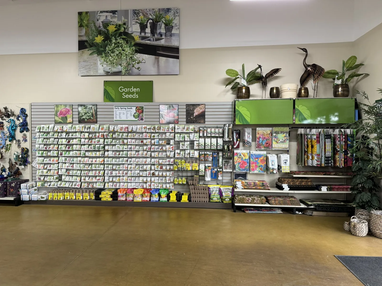 Indoor garden center display with various seed packets, gardening tools, decorative plants, and accessories.