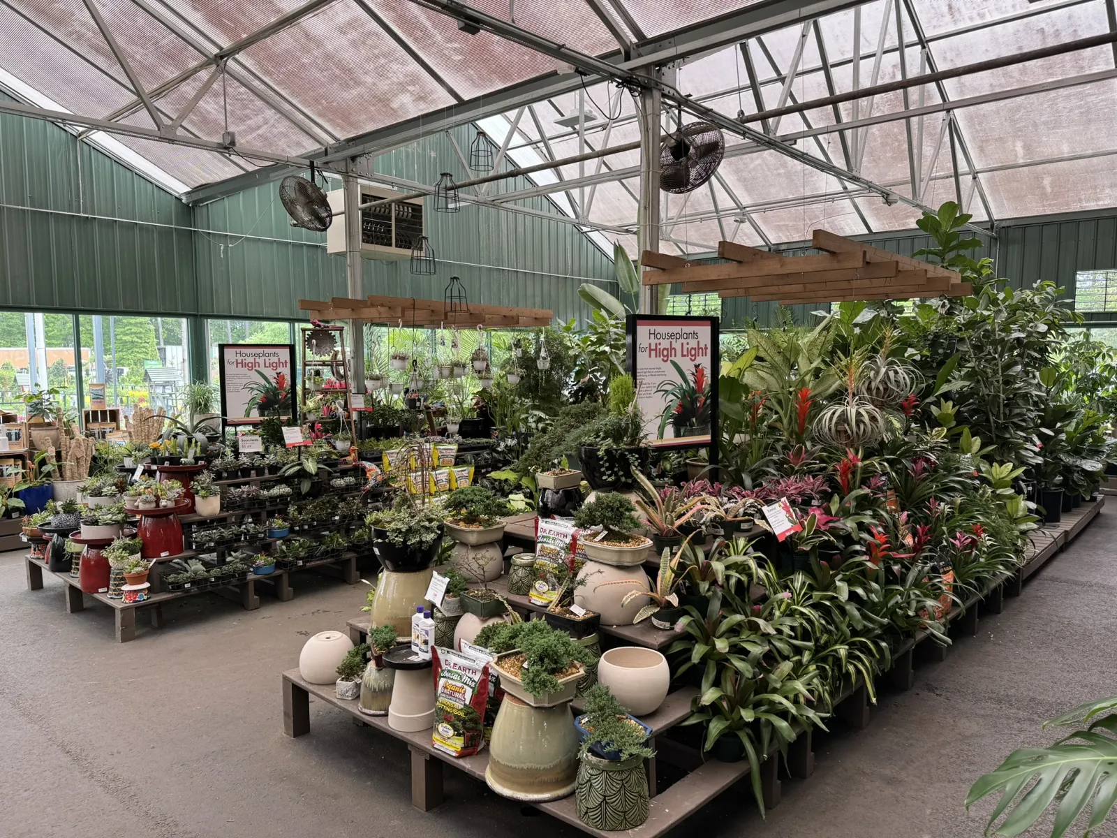 Indoor garden center with various houseplants and pots under translucent roofing for natural light.