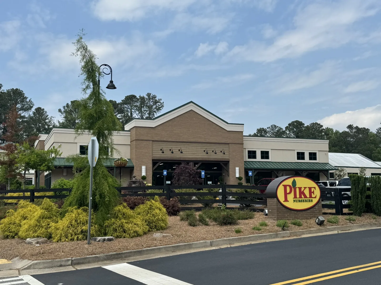 Pike Nurseries storefront with landscaping, green plants, and clear sky during daytime.