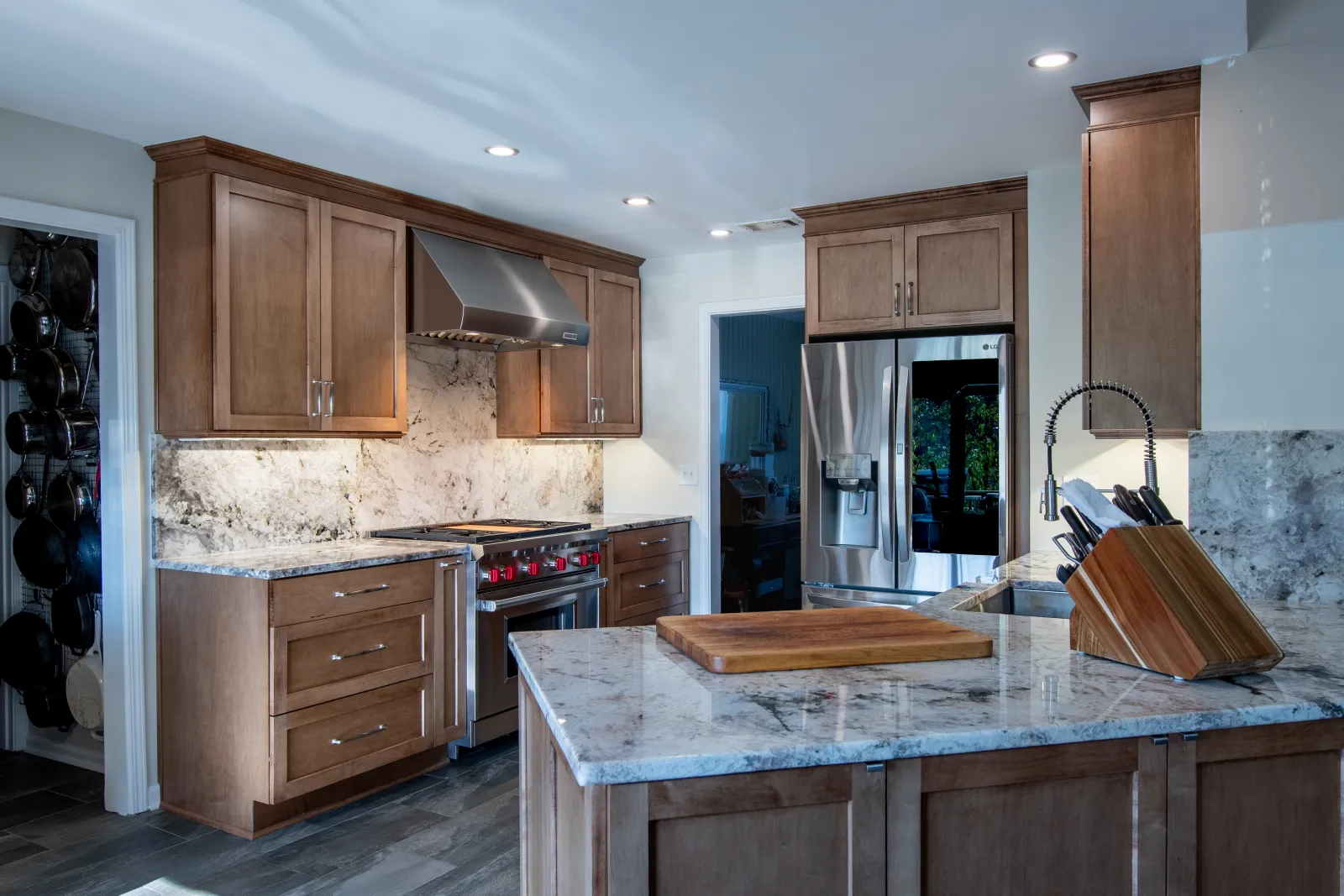 Modern kitchen with wooden cabinets, granite countertops, stainless steel appliances, and a large island with cutting board.
