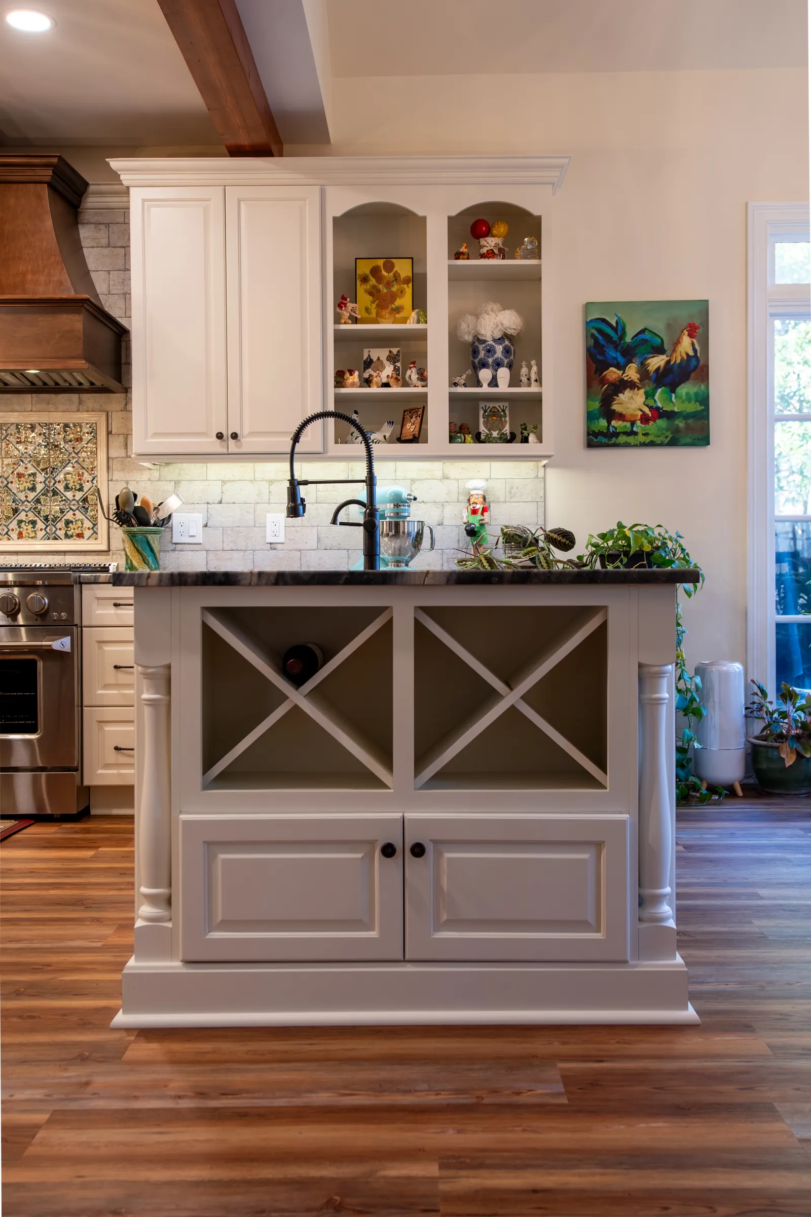 Modern kitchen island with farmhouse sink, white cabinetry, hardwood floors, and decorative shelves with plants and art.