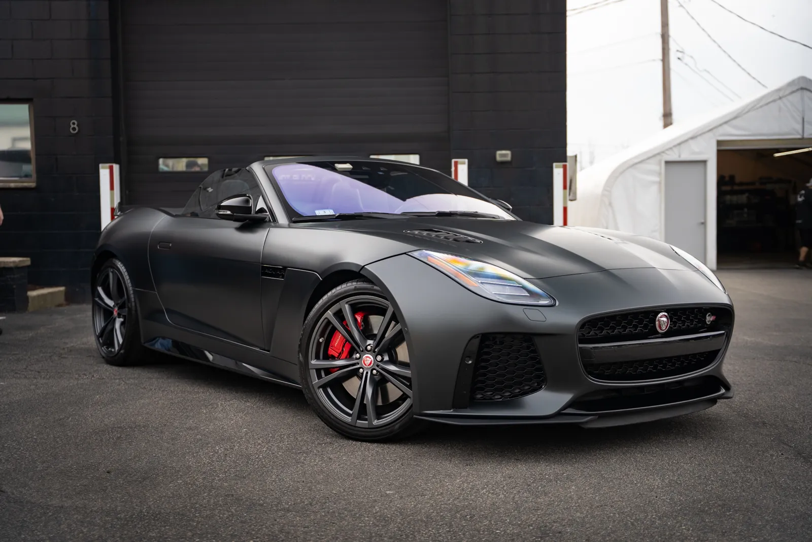 Matte black Jaguar sports convertible parked outdoors with red brake calipers and sleek design details