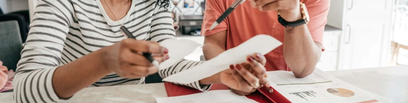 Couple reviewing documents and receipts together at home with TurboTax logo in white kitchen setting