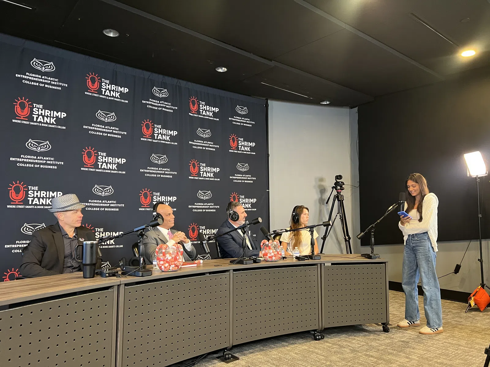 Judges seated at a panel for The Shrimp Tank event at Florida Atlantic University, with a contestant speaking.