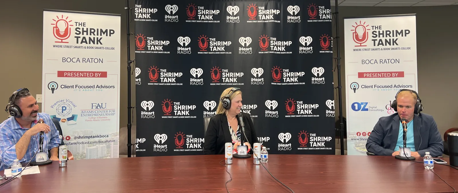 a man and woman sitting at a table with microphones and a sign