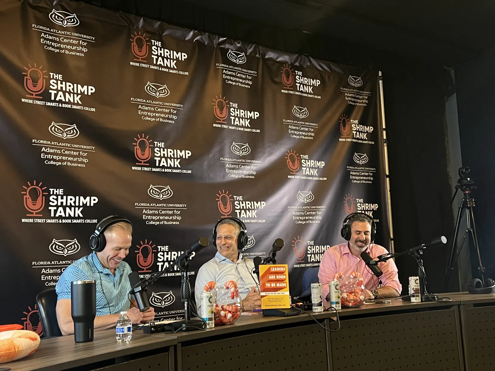 a group of people sitting at a table with microphones and a large banner behind them