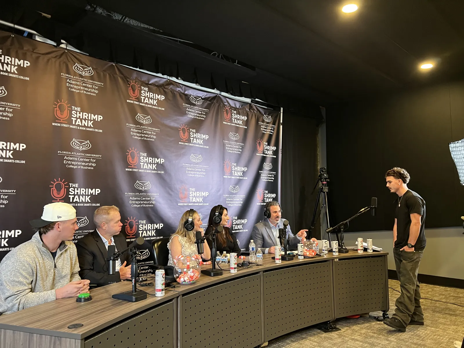 Panel of five judges at The Shrimp Tank event evaluating a young presenter in a studio setting.