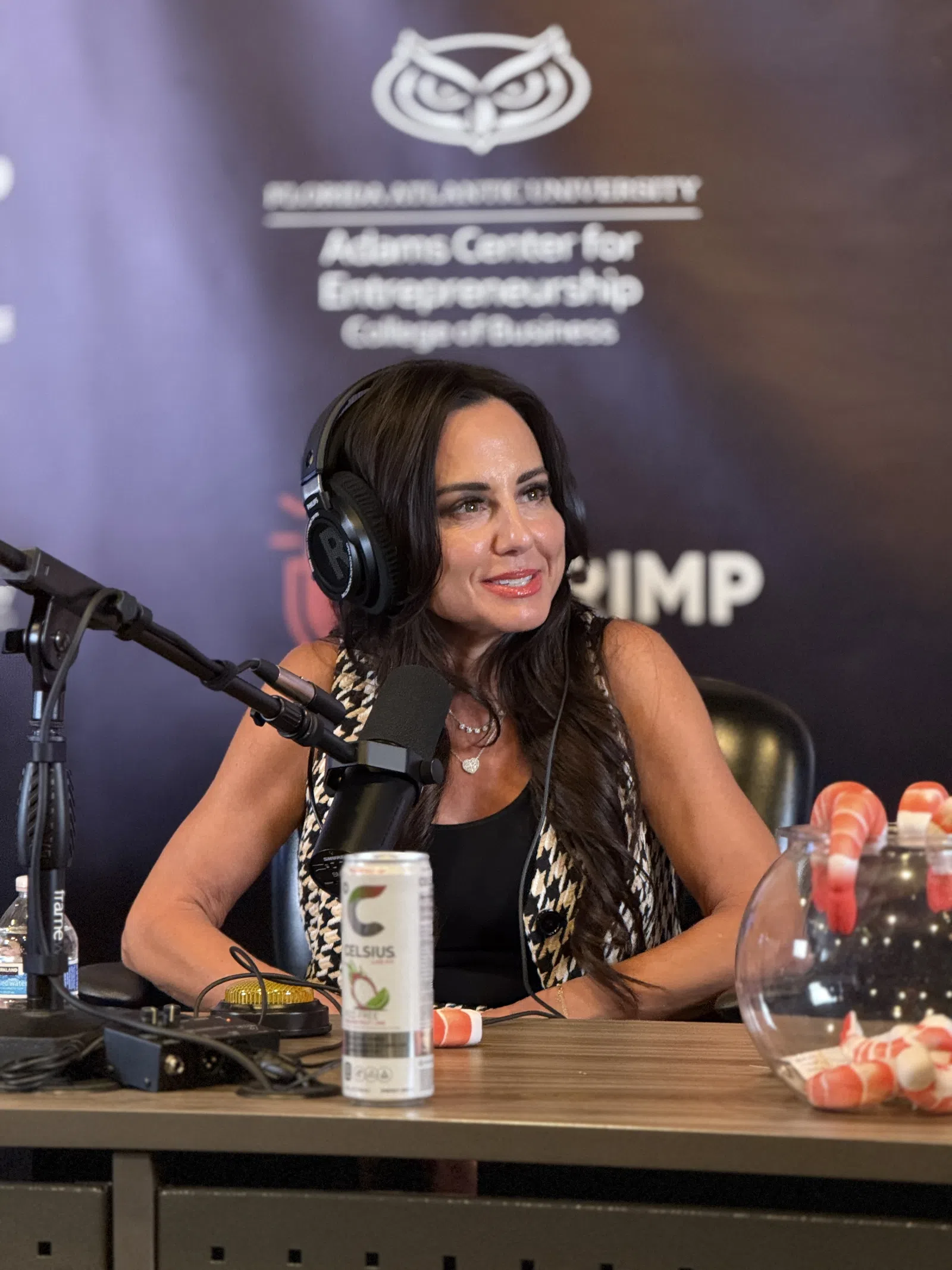Woman with headphones speaking into a microphone during a podcast at Florida Atlantic University's entrepreneurship center.