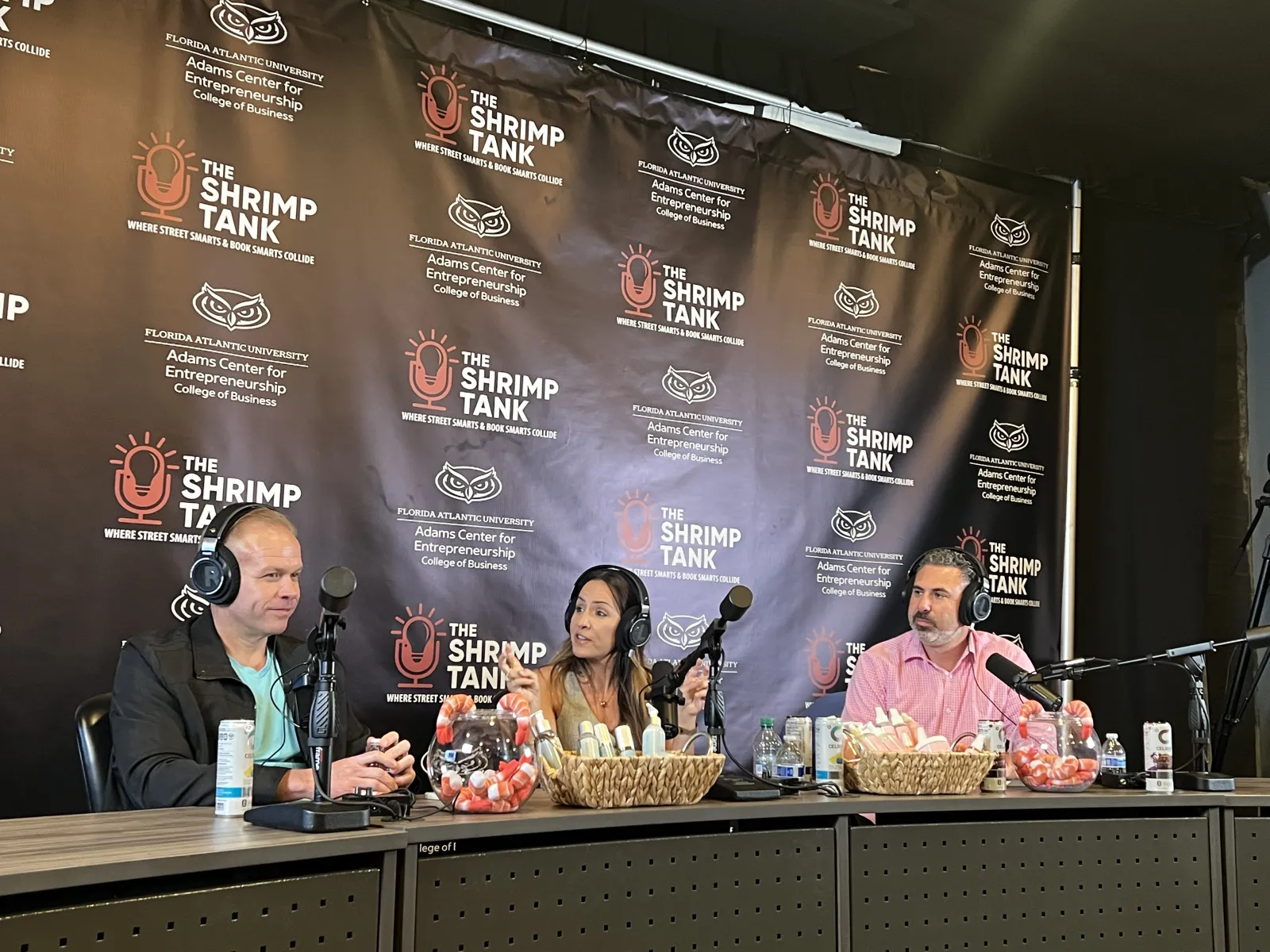 a group of people sitting at a table with microphones and food