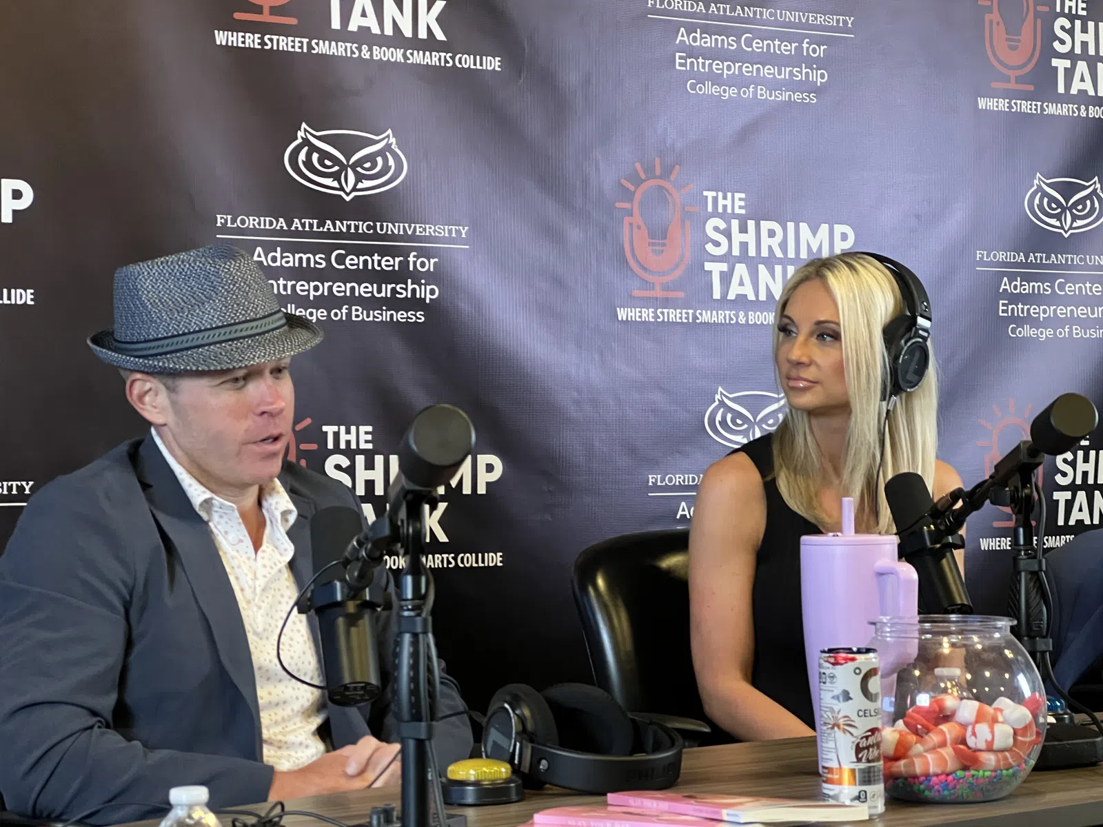 Two podcast hosts speaking into microphones during a recording at The Shrimp Tank studio.