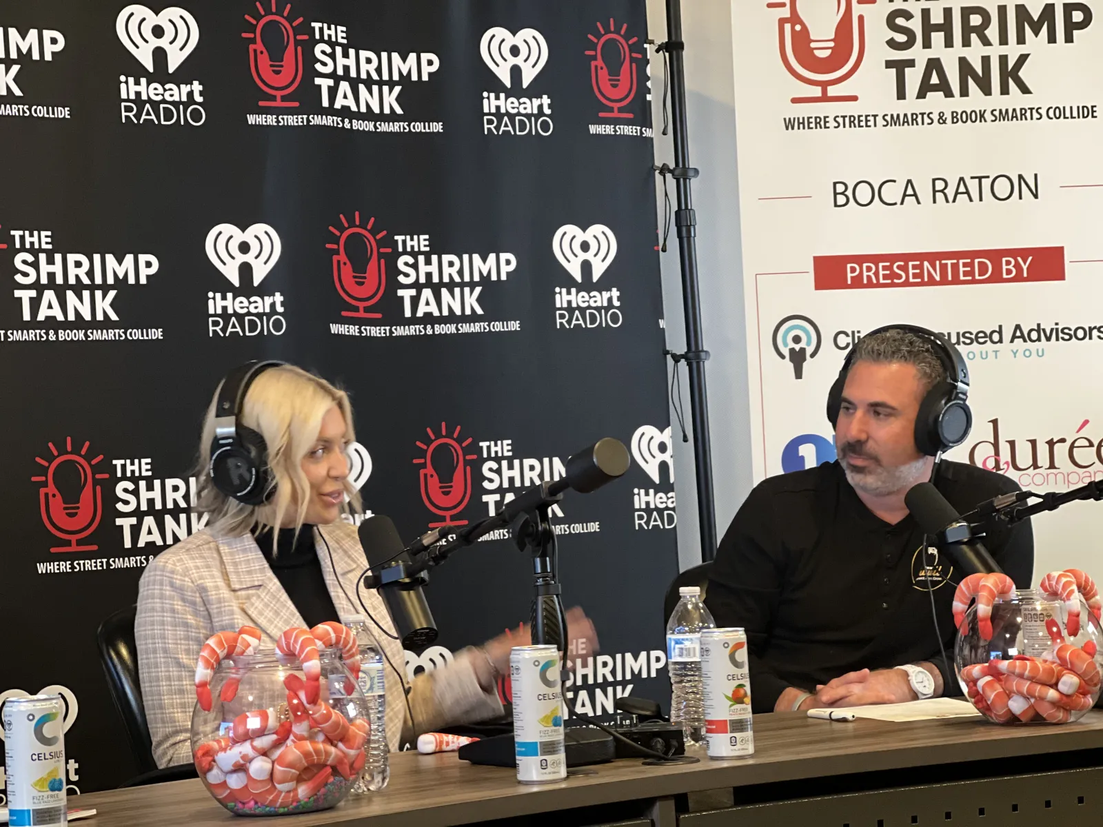 a man and woman sitting at a table with microphones