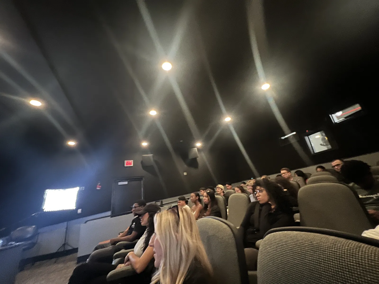 a group of people sitting in a room with a large screen