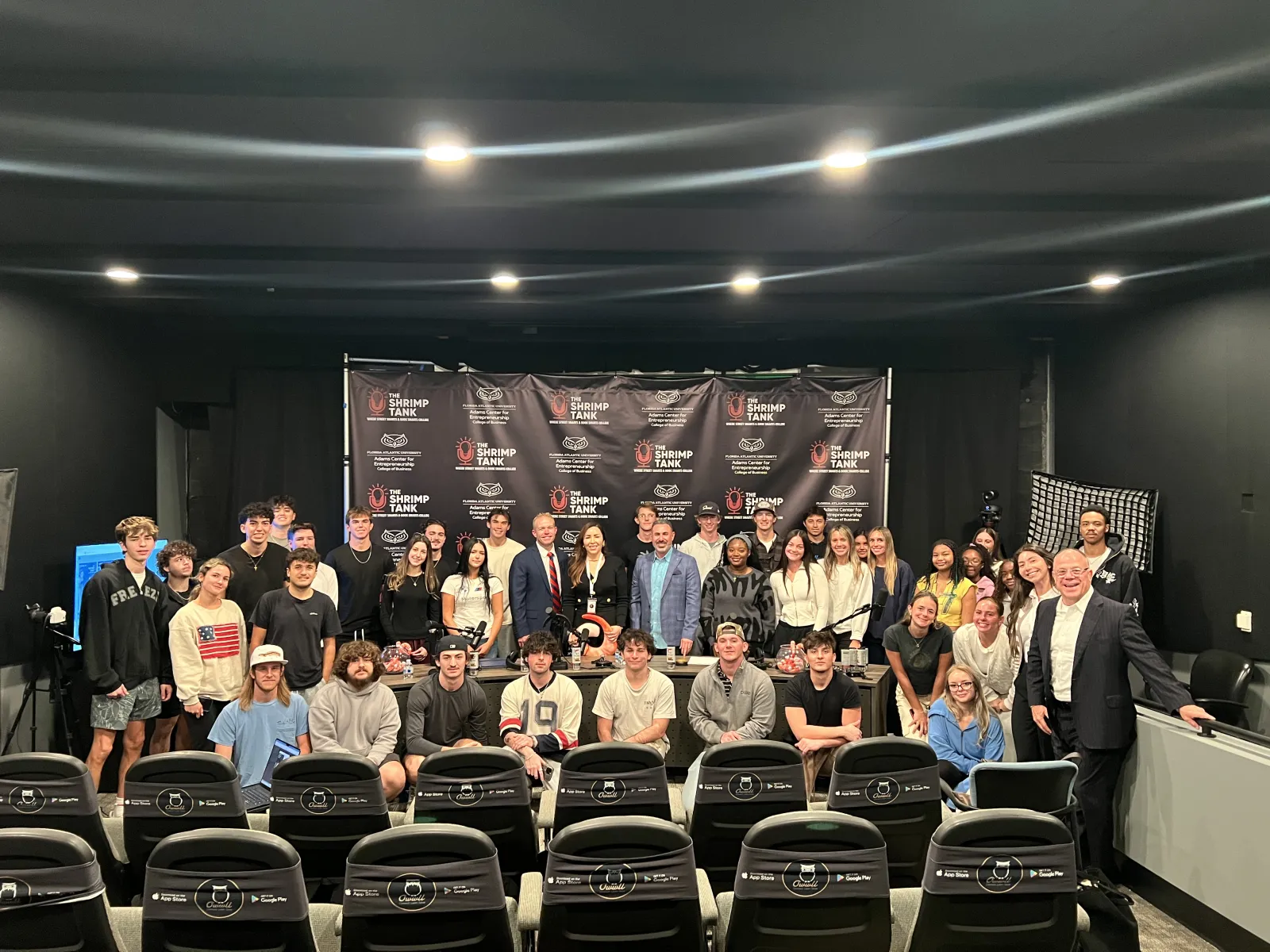 Group of diverse people posing in front of Shrimp Tank Media branding backdrop in a studio setting
