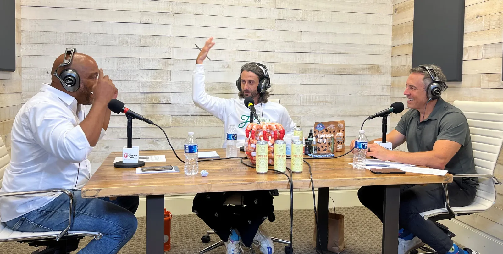 a group of people sitting at a table with microphones and drinks