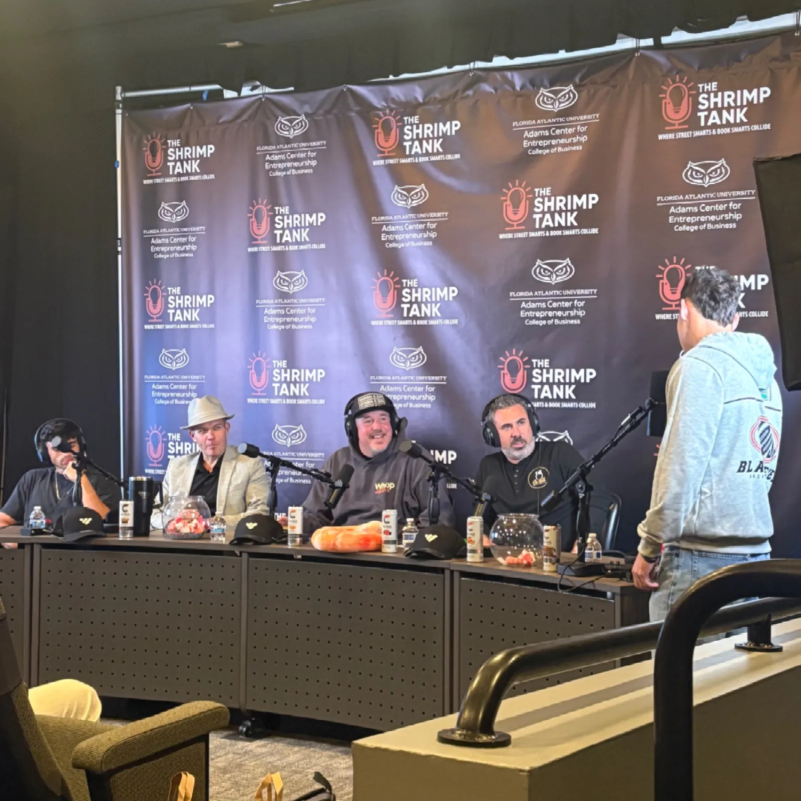 Podcast recording at The Shrimp Tank with hosts and guest at microphones in studio setting