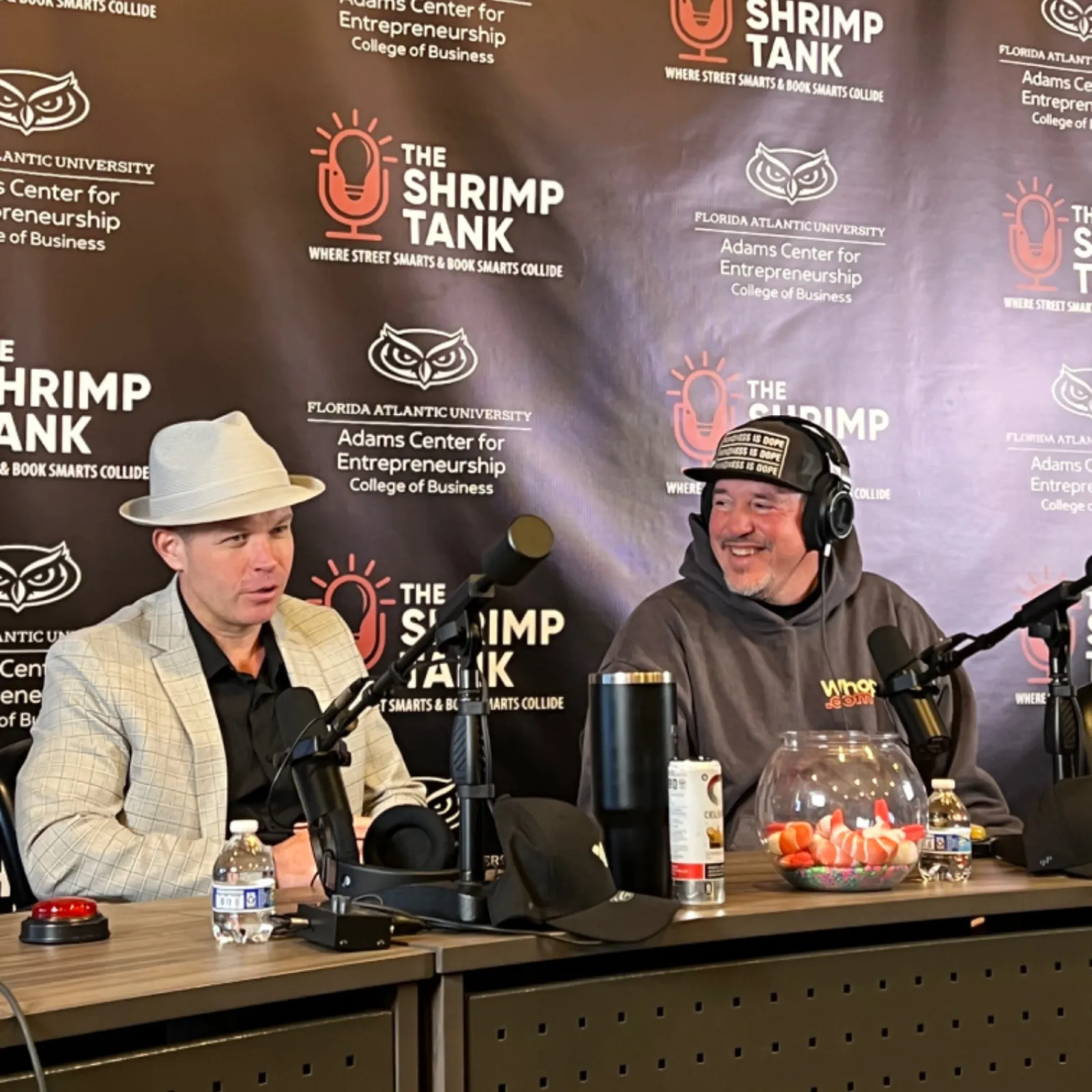 Two men recording a podcast at The Shrimp Tank with microphones and branded backdrop from Florida Atlantic University