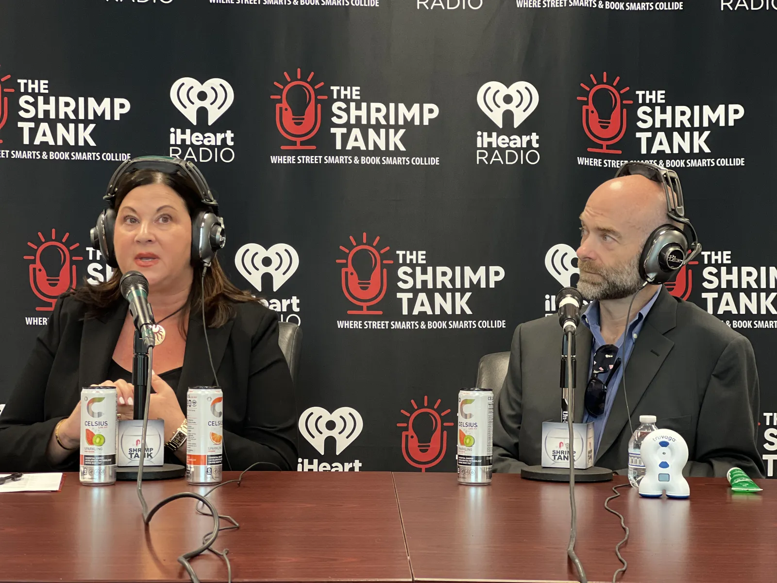 a man and woman sitting at a table with microphones