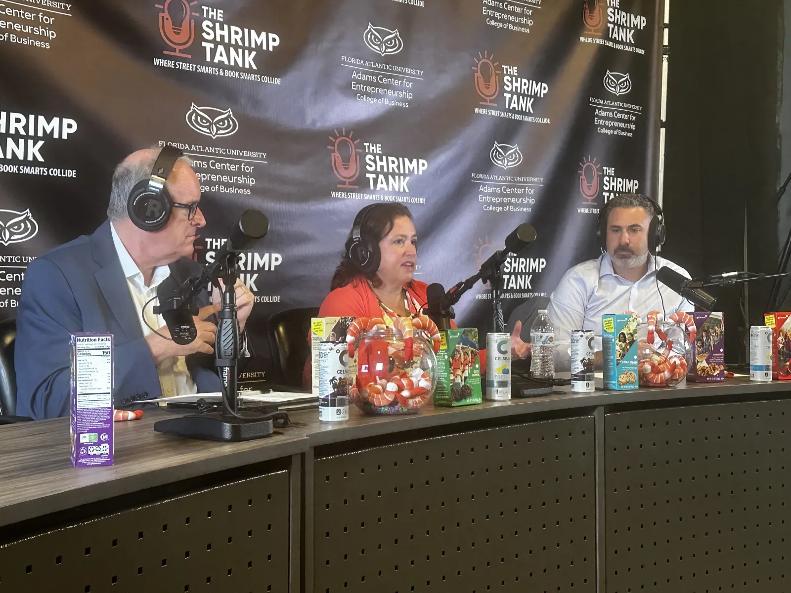 a group of people sitting at a table with microphones and drinks