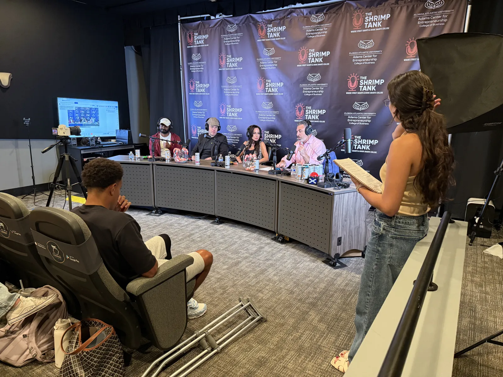 Panelists and host engaged in discussion at The Shrimp Tank event with audience and recording setup in studio