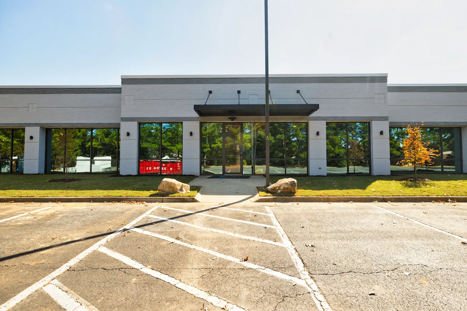 Empty parking lot in front of a modern commercial building with glass doors and windows on a sunny day