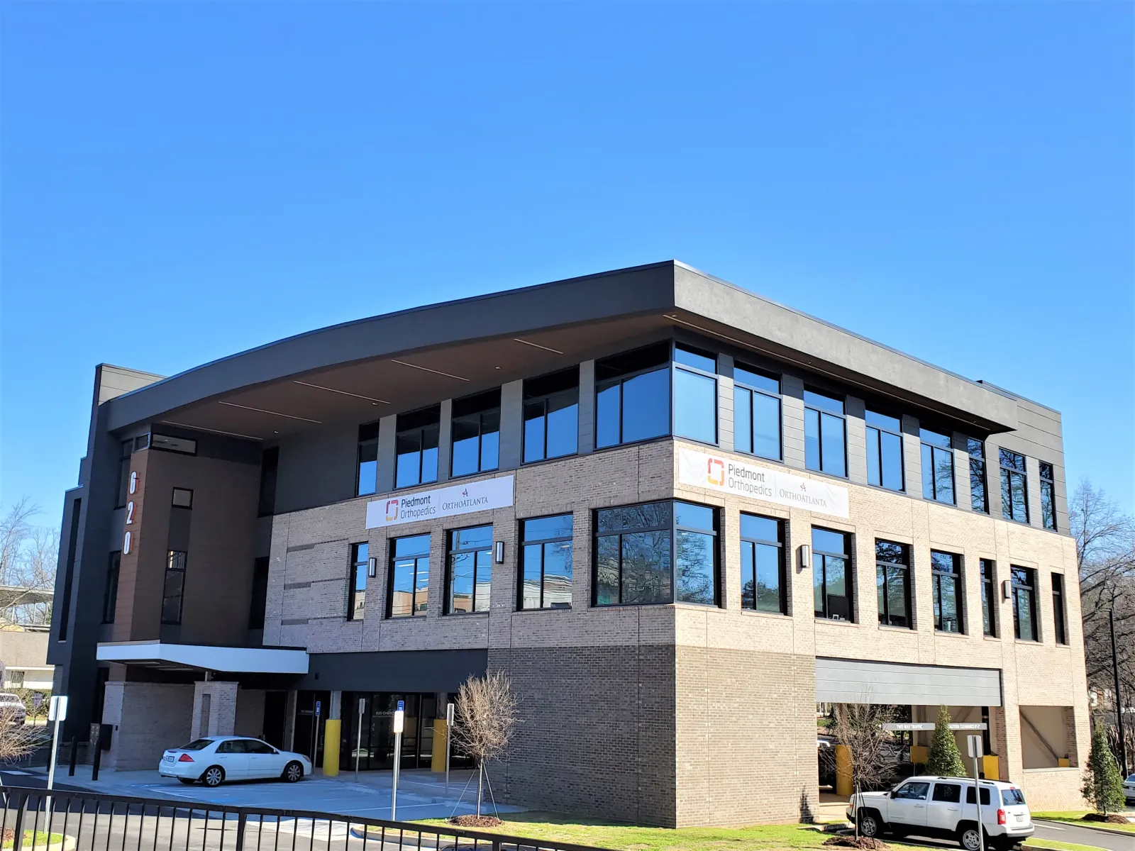 Modern three-story office building with large windows and clear blue sky background
