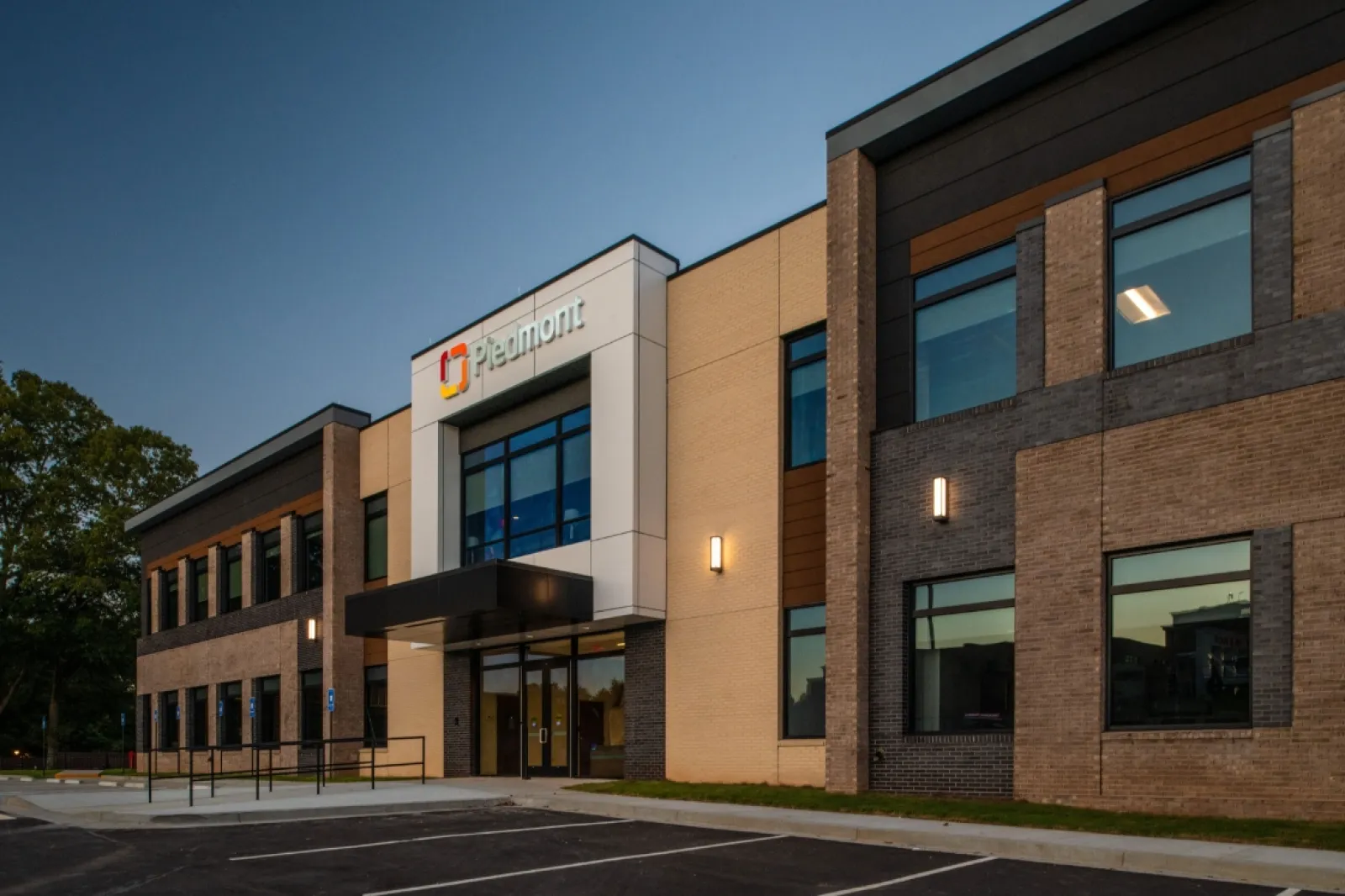 Modern Piedmont medical office building exterior at dusk with parking lot and illuminated signage.