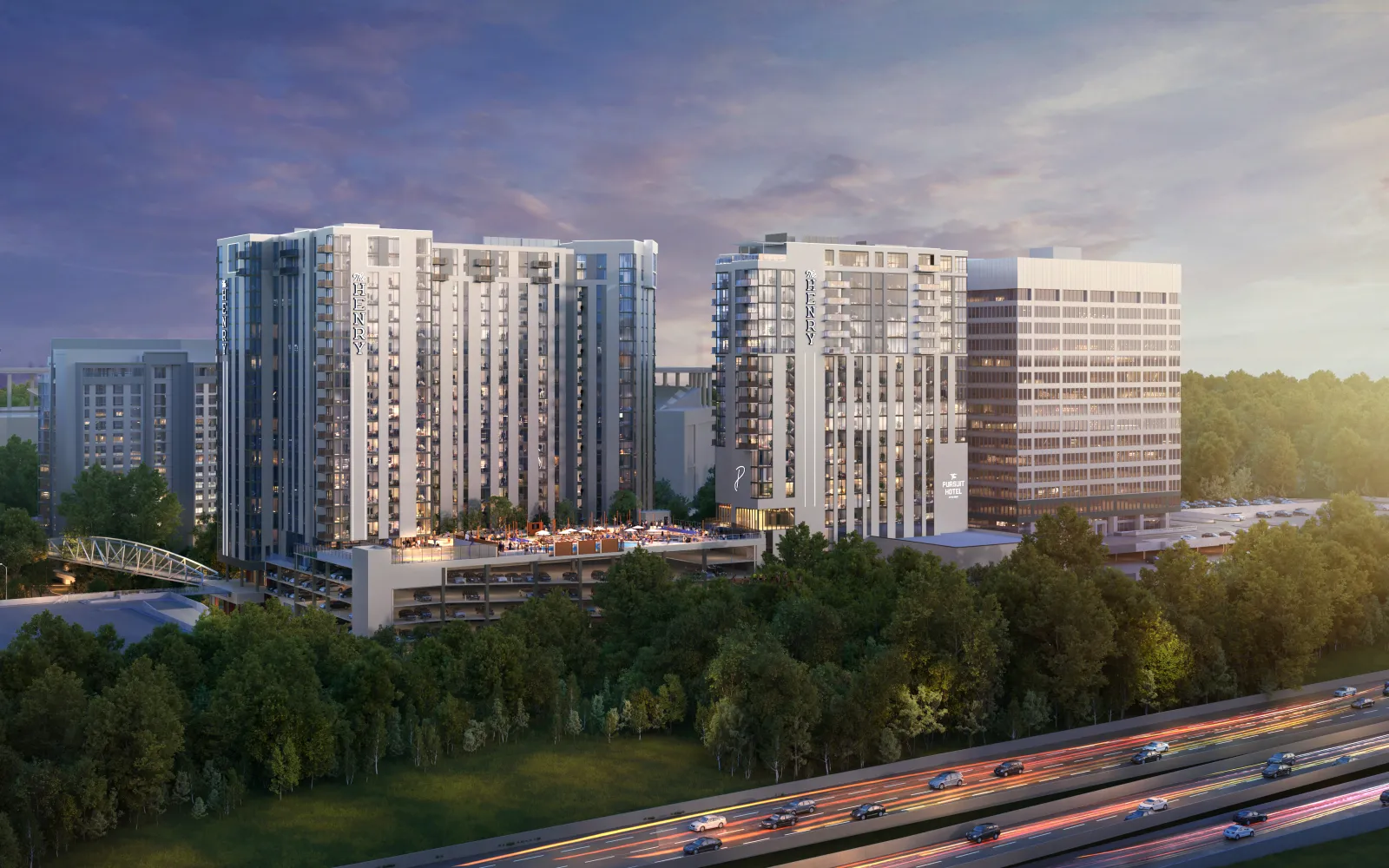 Modern residential and office buildings beside a highway with trees and a colorful sunset sky.