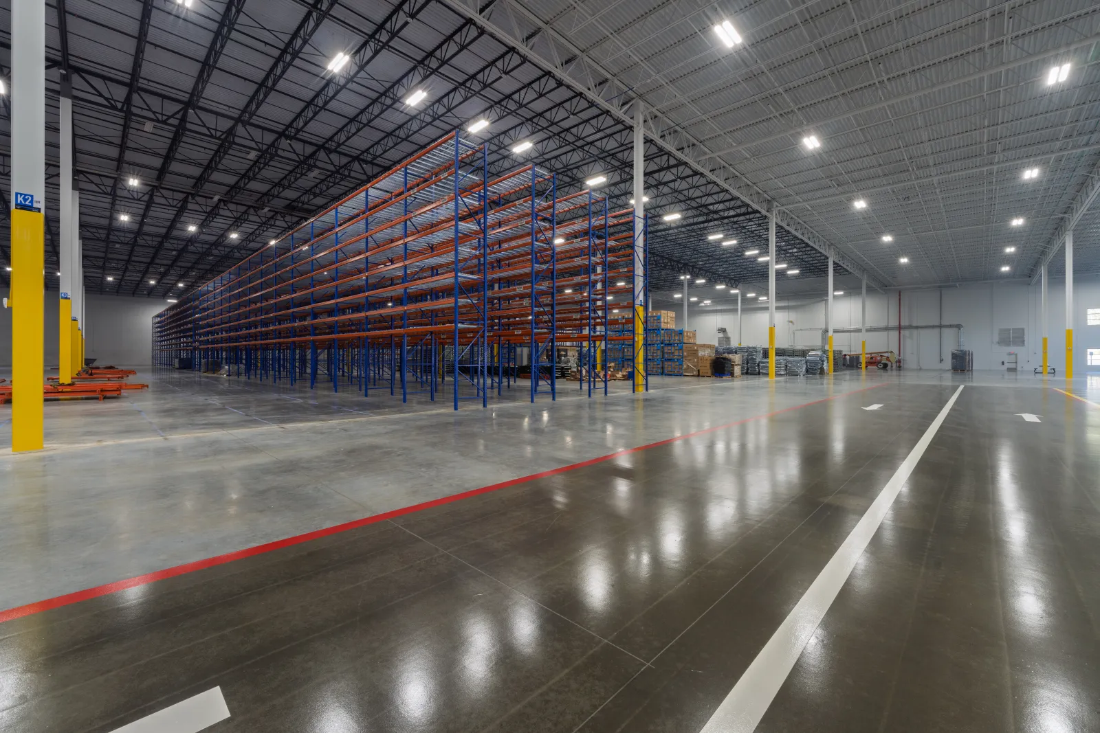 Spacious modern warehouse interior with tall empty storage racks and bright overhead lighting