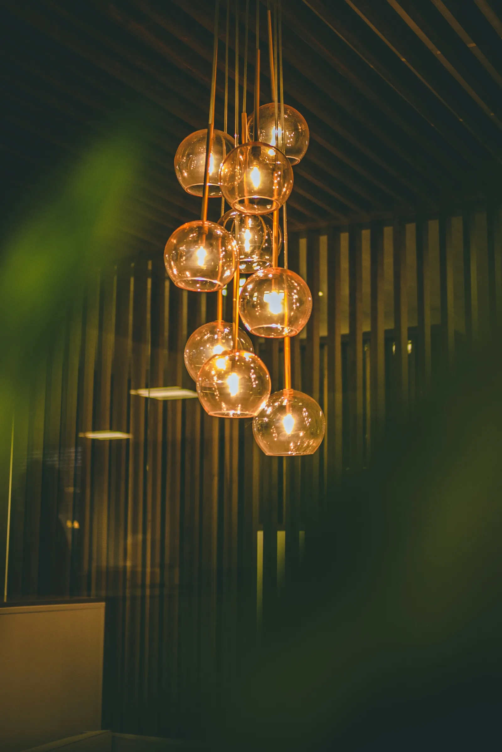 Modern hanging pendant lights with round glass globes glowing warmly in a dark, stylish interior space.