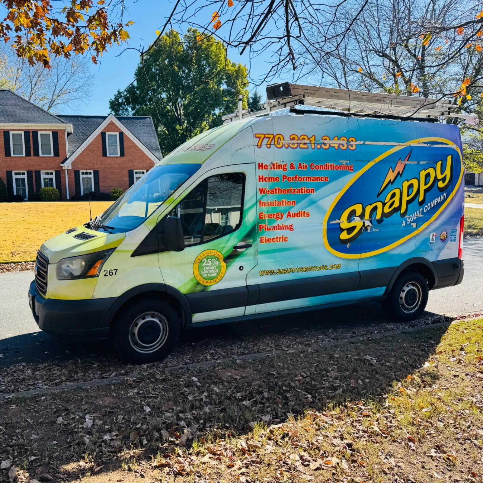Blue and yellow Snappy service van parked on a suburban street under autumn trees with home performance and plumbing services listed.