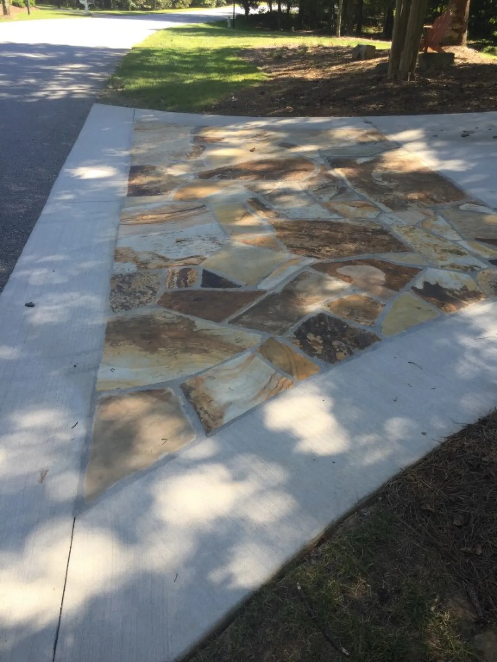 a stone walkway with grass and trees