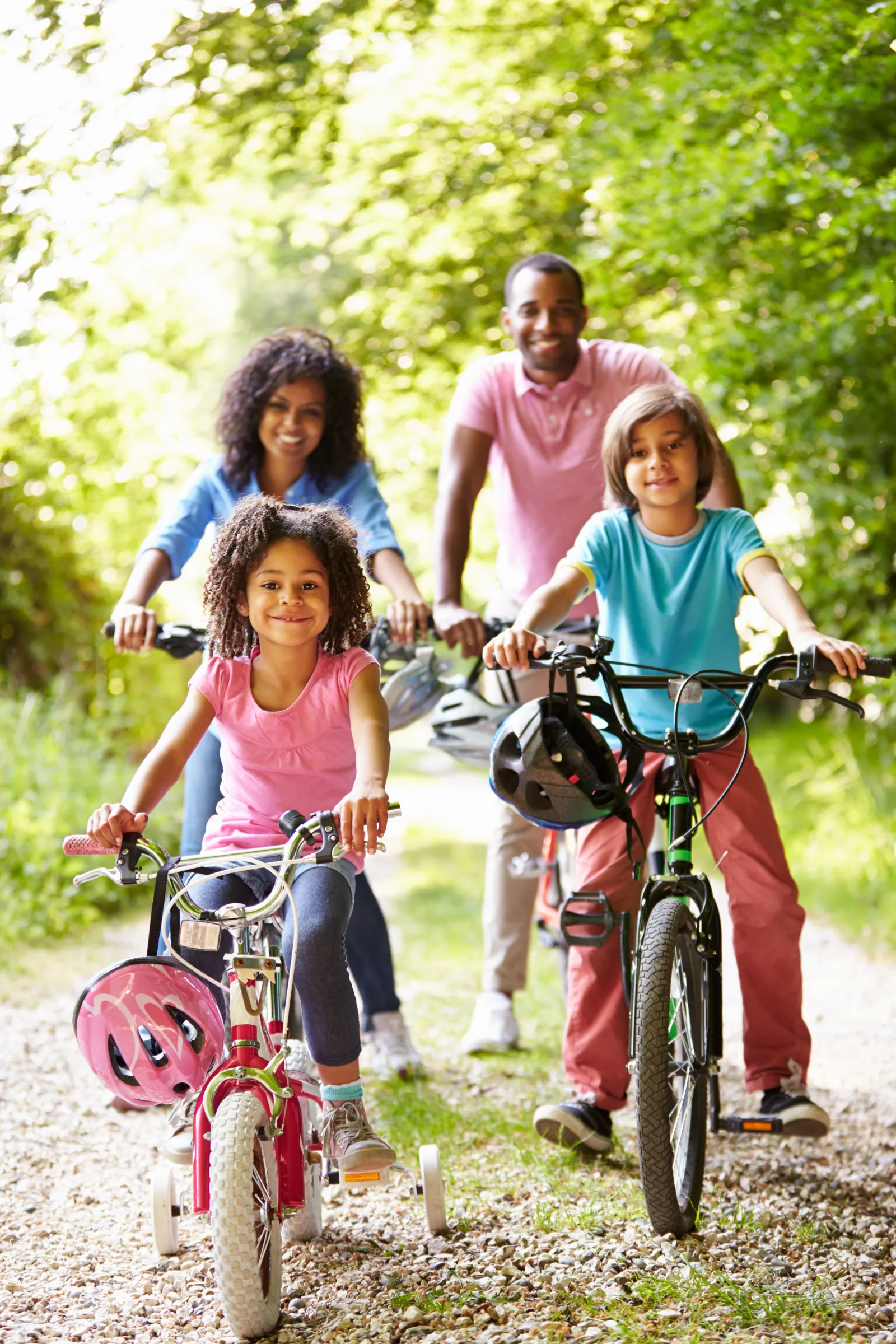 A family of four riding bikes together on a trail outdoors