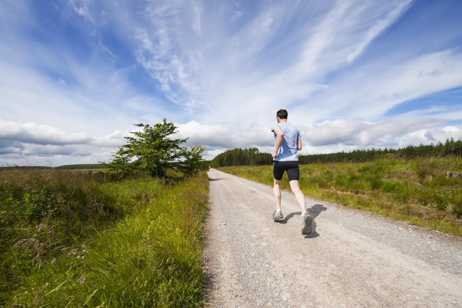 Man hitting physical activity goals by running along a trail outdoors