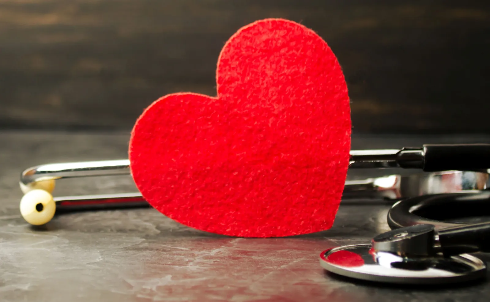 Red paper heart on the ground surrounded by a stethoscope