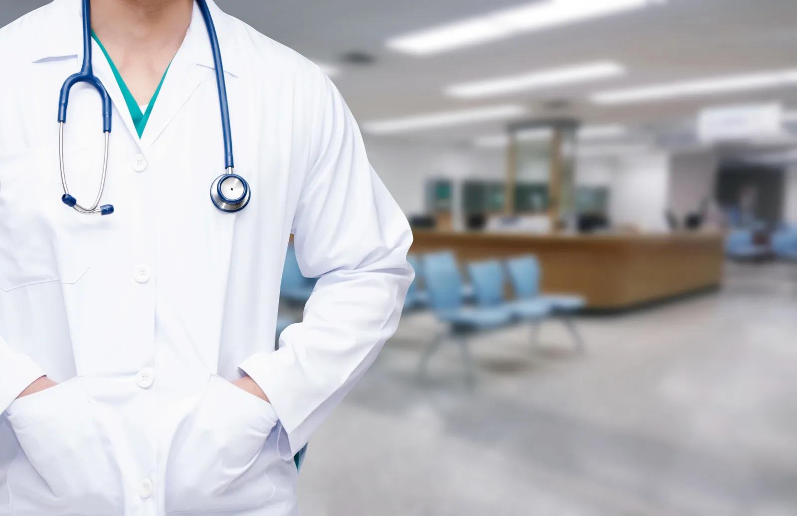 Doctor standing with their hands in the pockets of their lab coat in front of the waiting room