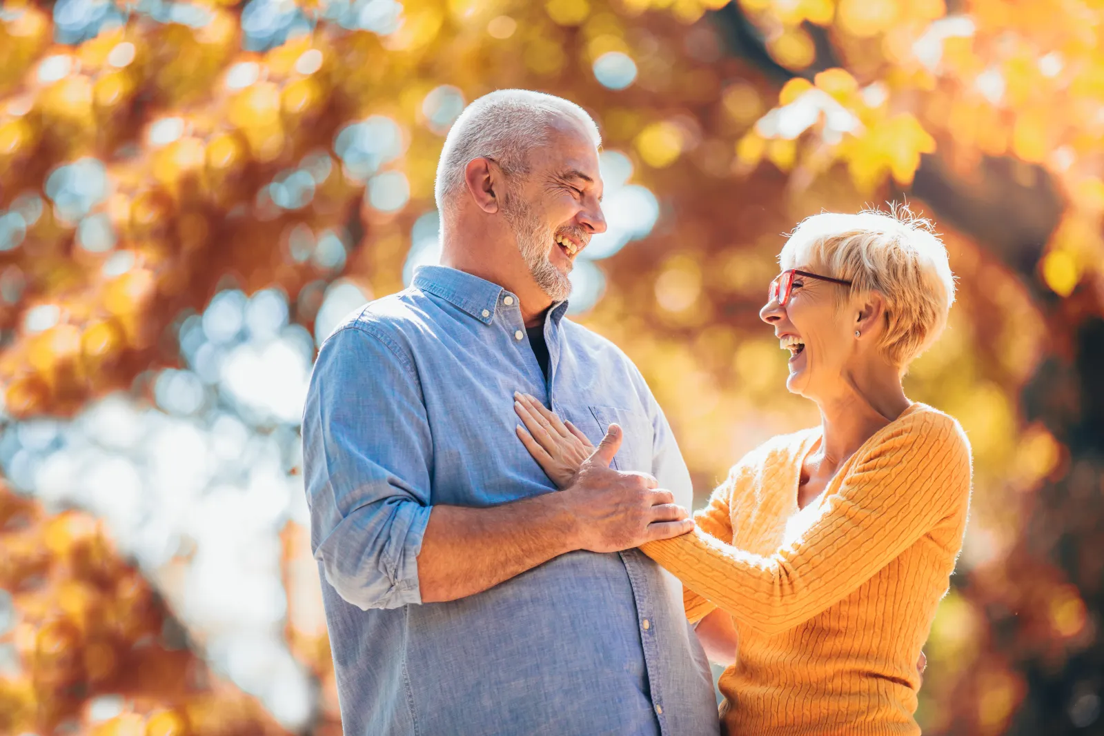 Healthy older couple laughing together outside during the fall season