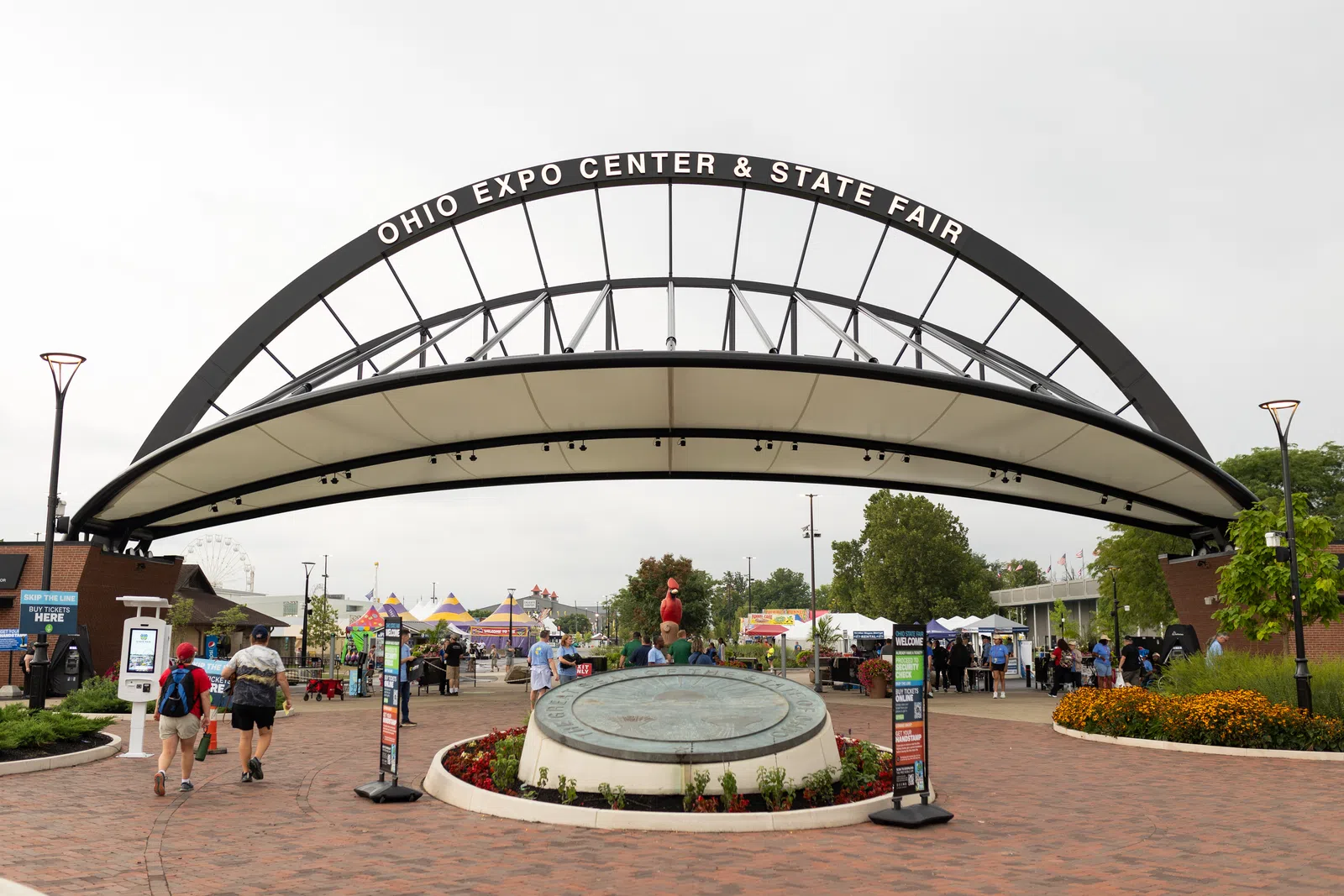 Entrance arch to Ohio Expo Center & State Fair with visitors and tents under cloudy sky