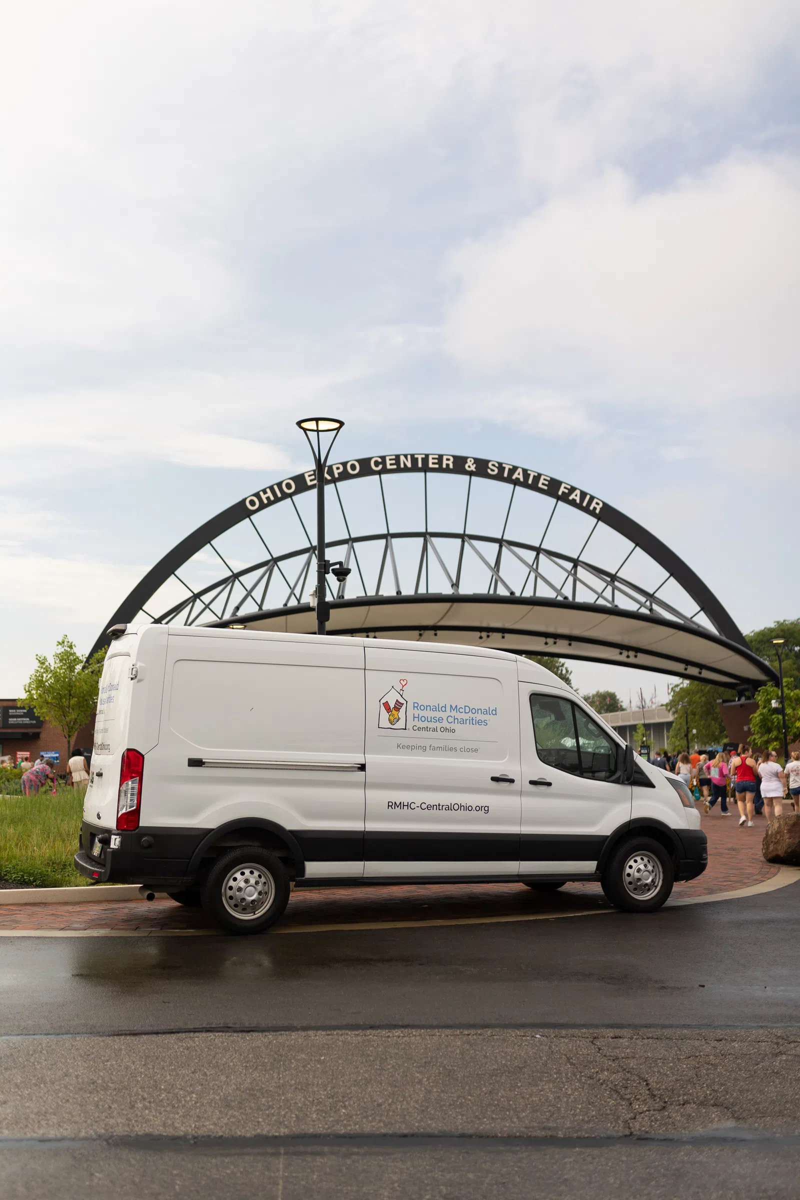 White Ronald McDonald House Charities van parked near Ohio Expo Center & State Fair entrance on a cloudy day.