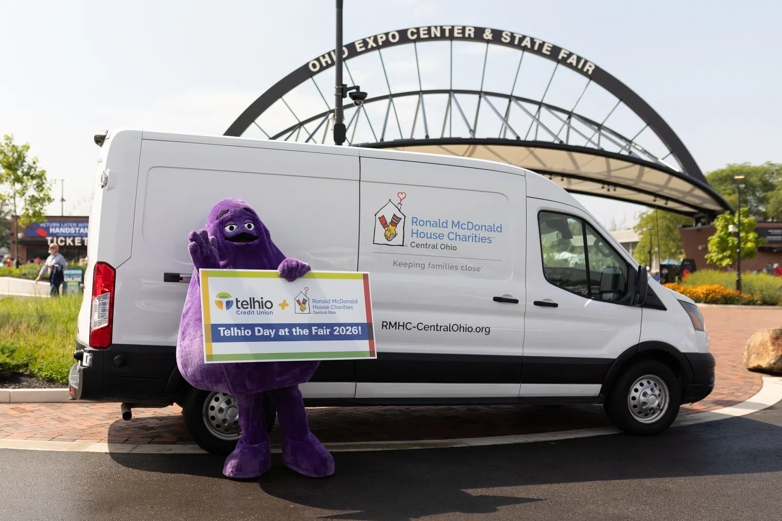 Purple mascot holding Telhio Day at the Fair 2026 sign next to Ronald McDonald House Charities van at Ohio Expo Center.