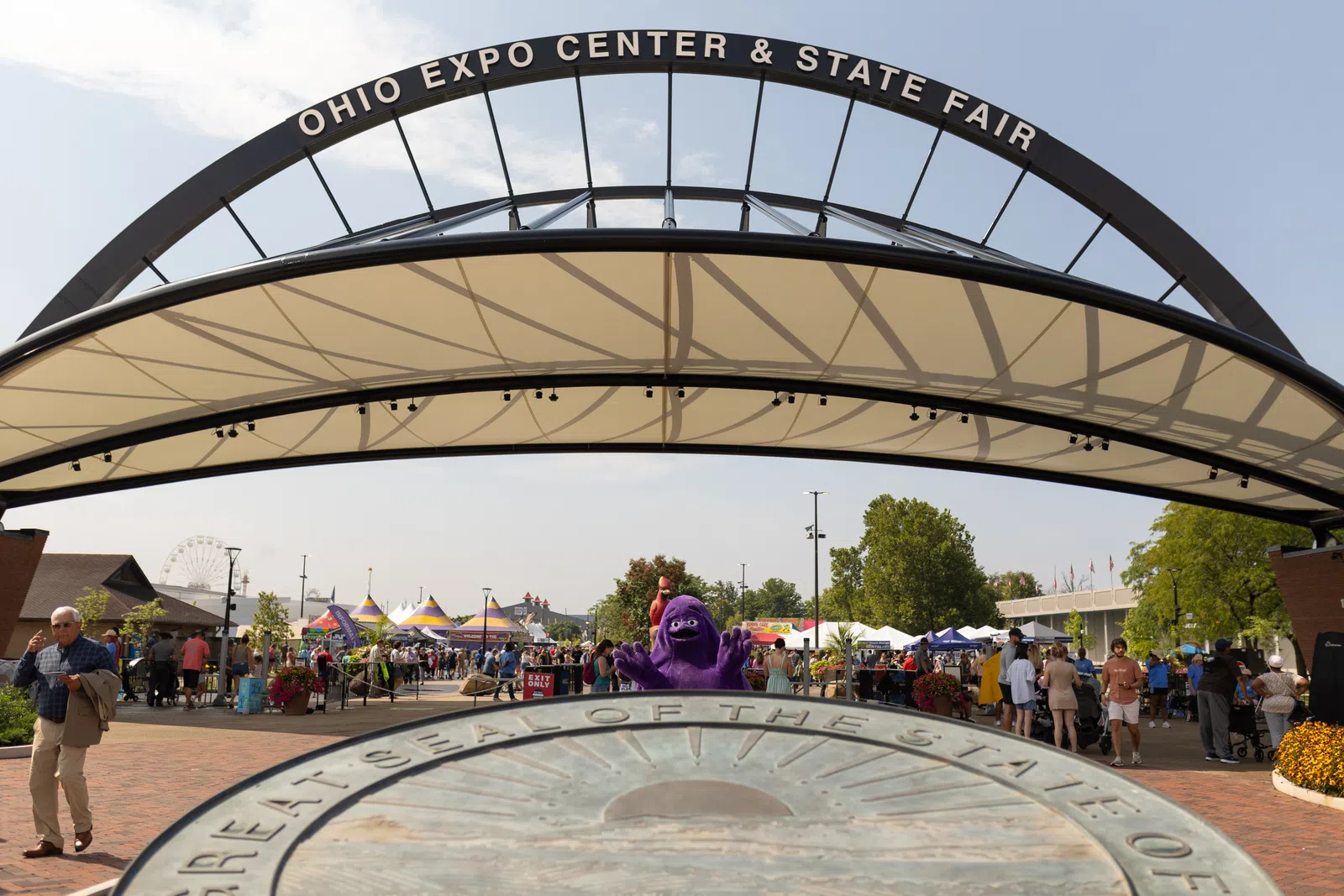 Entrance arch to Ohio Expo Center & State Fair with crowds and festival tents on a sunny day