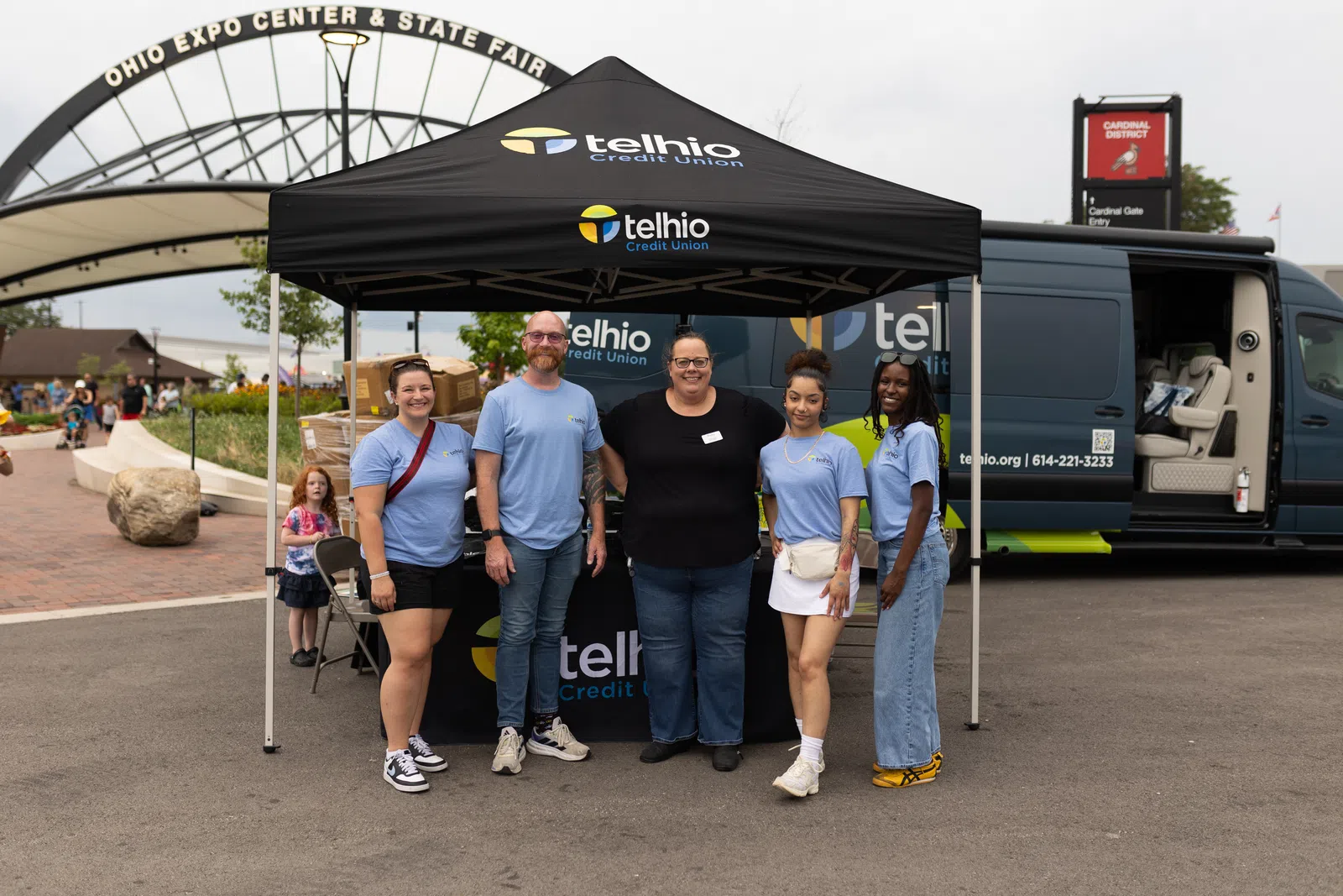 Group of five people standing under a Telhio Credit Union tent at Ohio Expo Center and State Fair entrance.