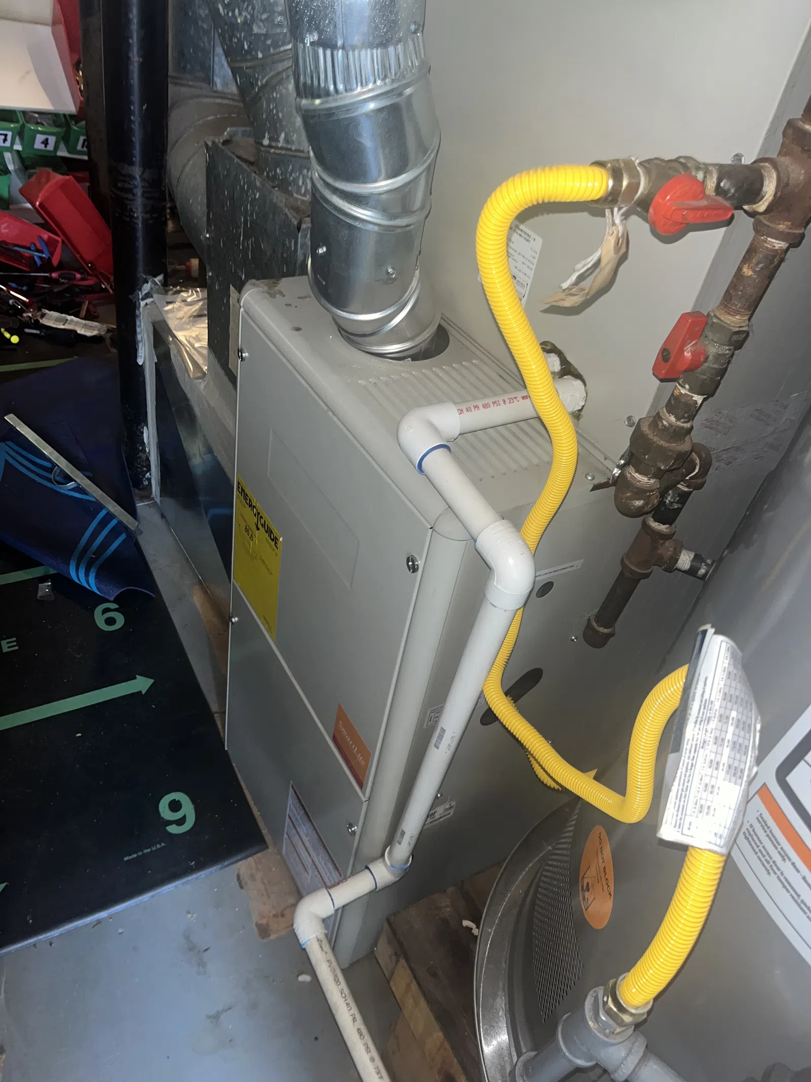 AC Preventative Maintenance in Tucker, Atlanta by The Air Company of GA. Close-up of a home furnace system with metal vent pipes and yellow gas tubing connected to plumbing.