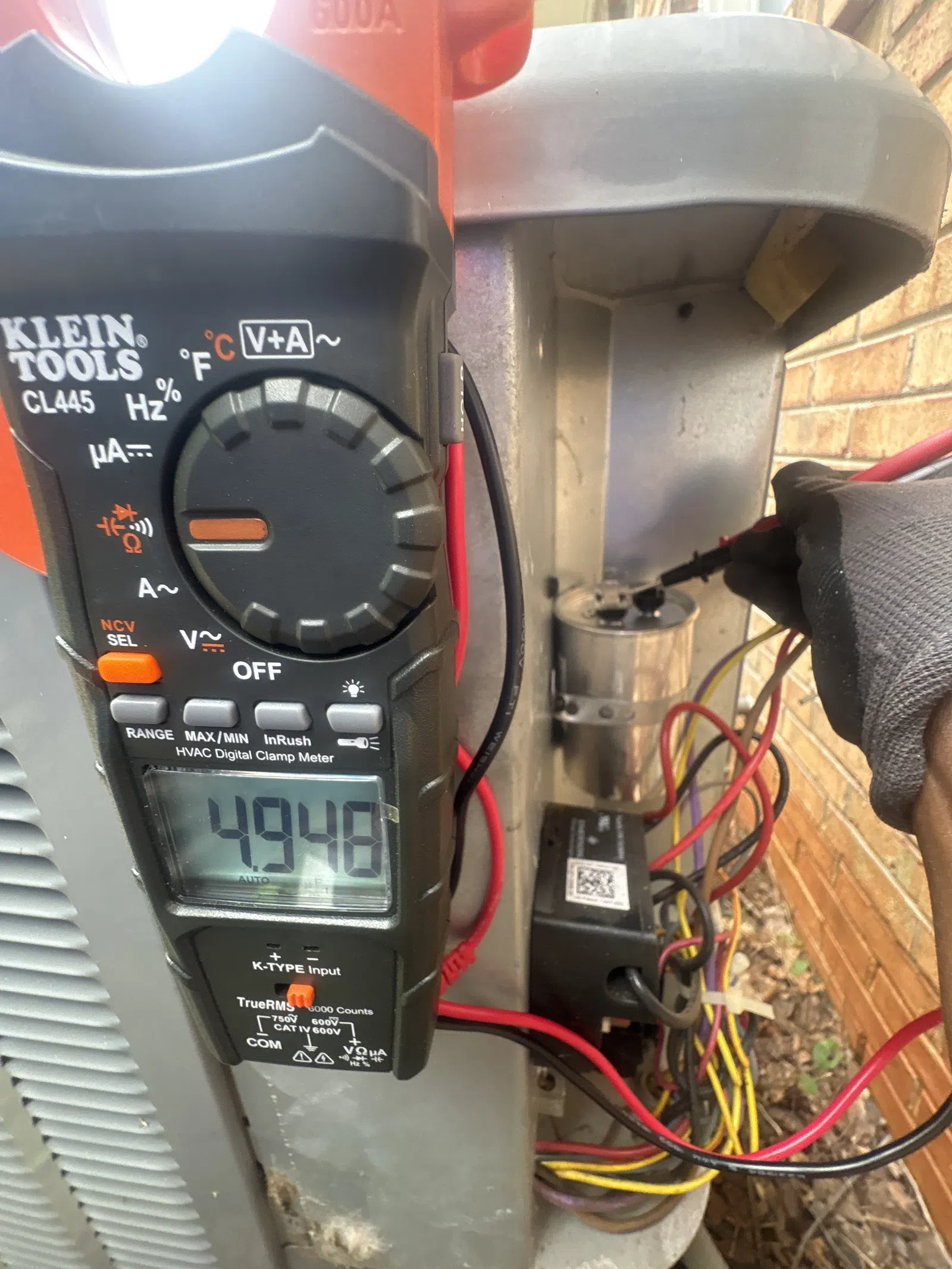 AC Repairs in Tucker Atlanta by The Air Company of GA. HVAC technician using a Klein Tools digital clamp meter to measure electrical current on an outdoor condenser unit.
