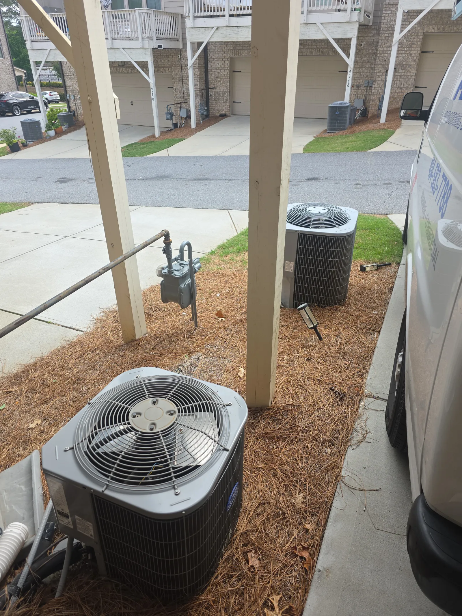 Atlanta Doraville AC Repair by The Air Company of GA. Outdoor air conditioning units installed beside a porch with pine needle ground cover and nearby gas meter