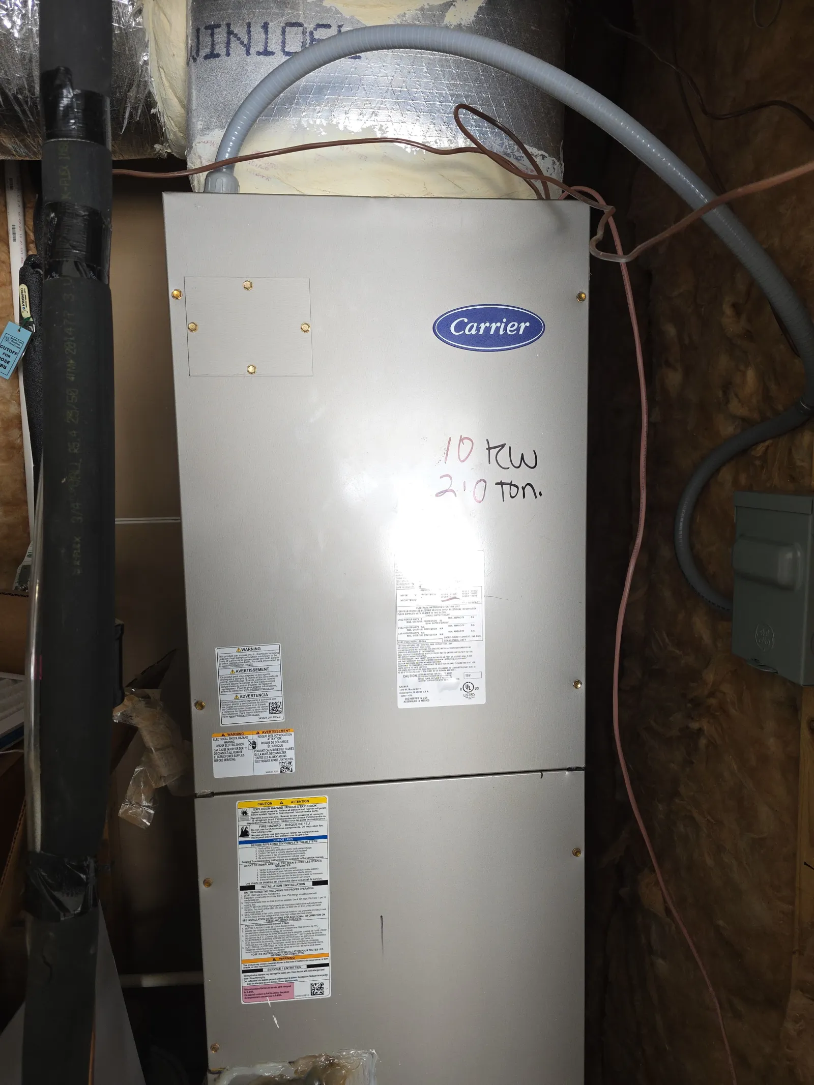 Atlanta Doraville AC Repair by The Air Company of GA.  Carrier HVAC unit installed in an insulation-lined utility space with pipes and wiring visible.
