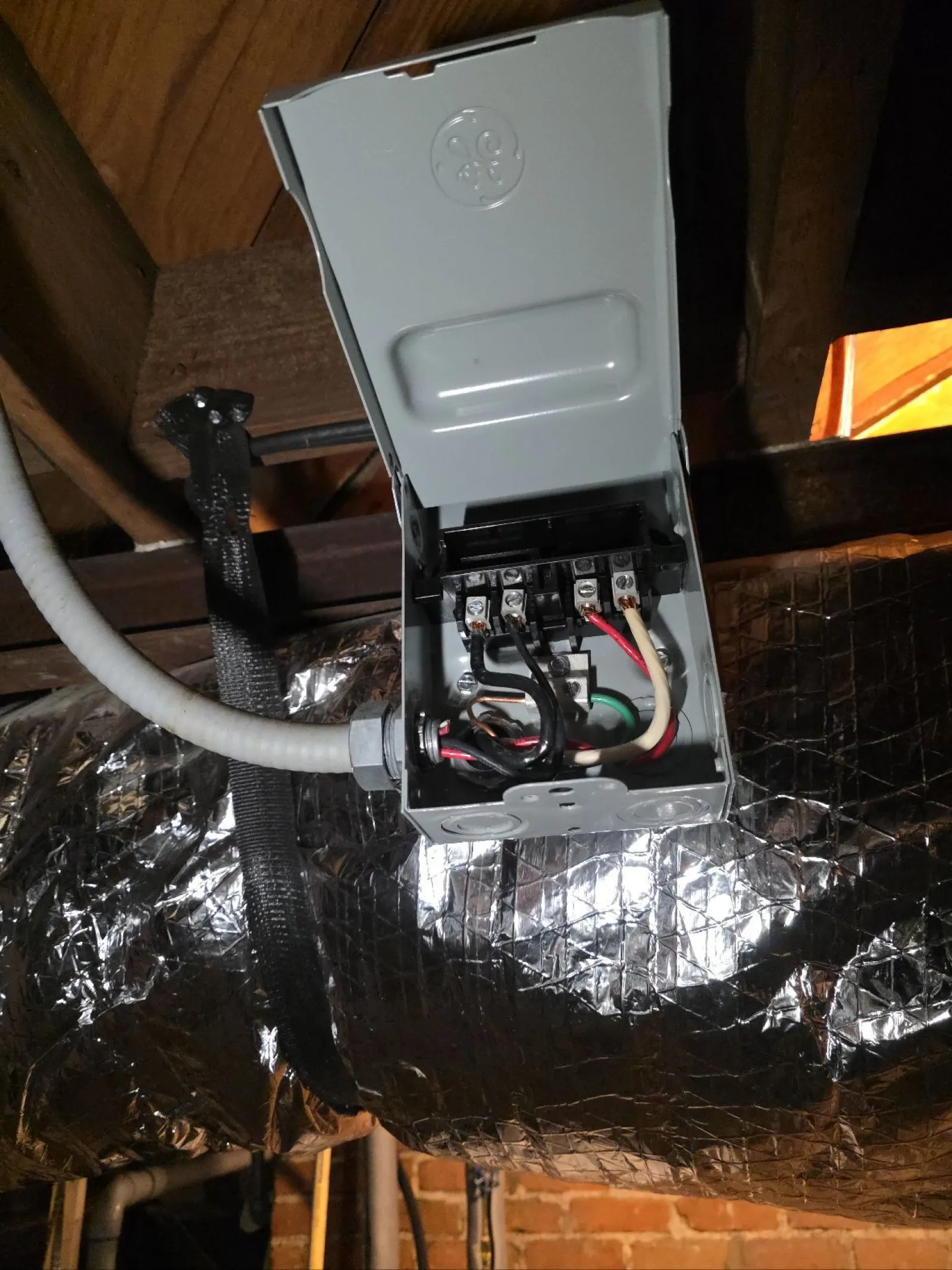 Atlanta HVAC Residential Repair by The Air Company of GA. Open electrical junction box with connected wires mounted near insulated ductwork in a basement.