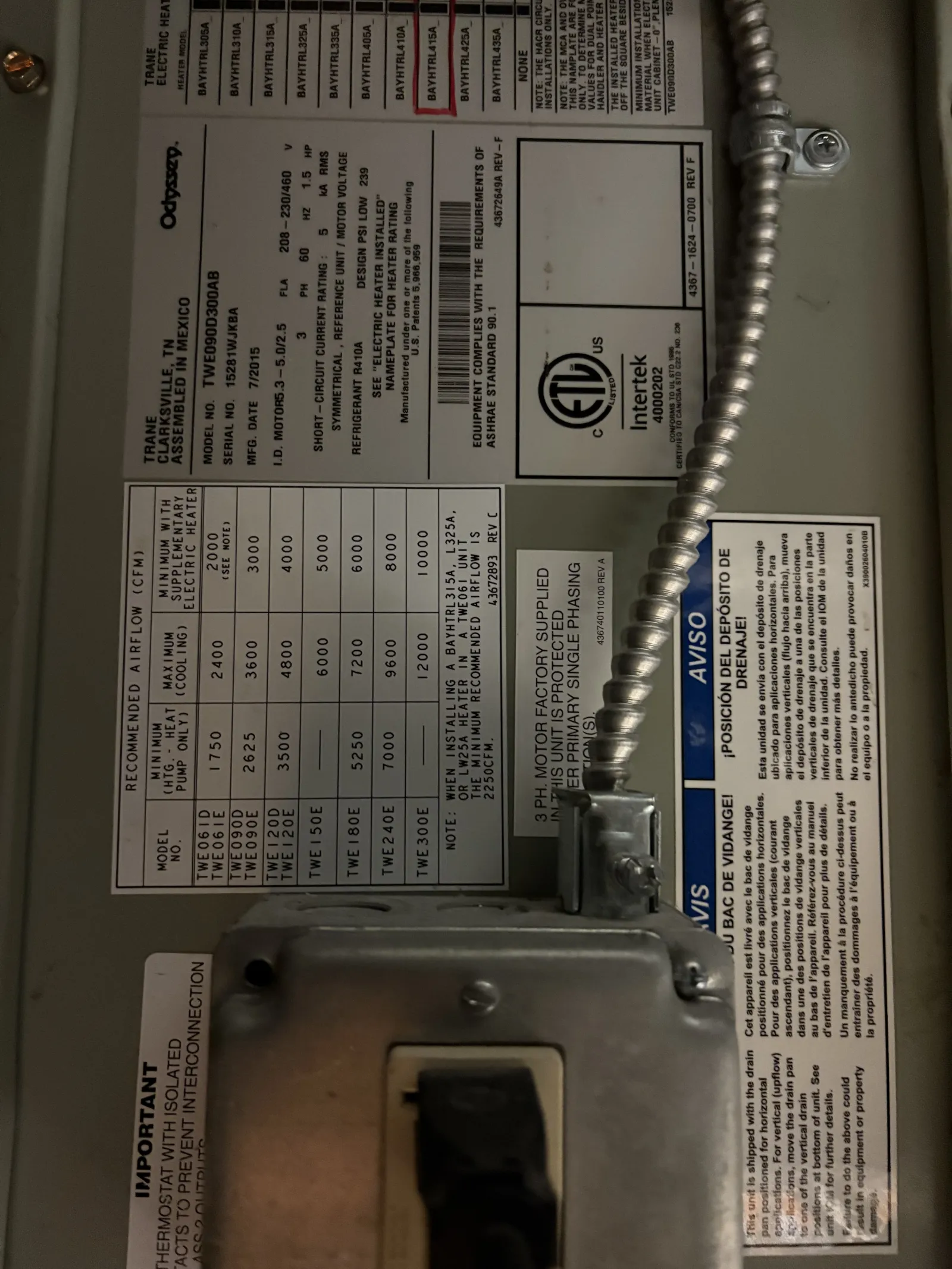 Close-up of a Trane electric heater specification label and wiring connection box with electrical conduit.