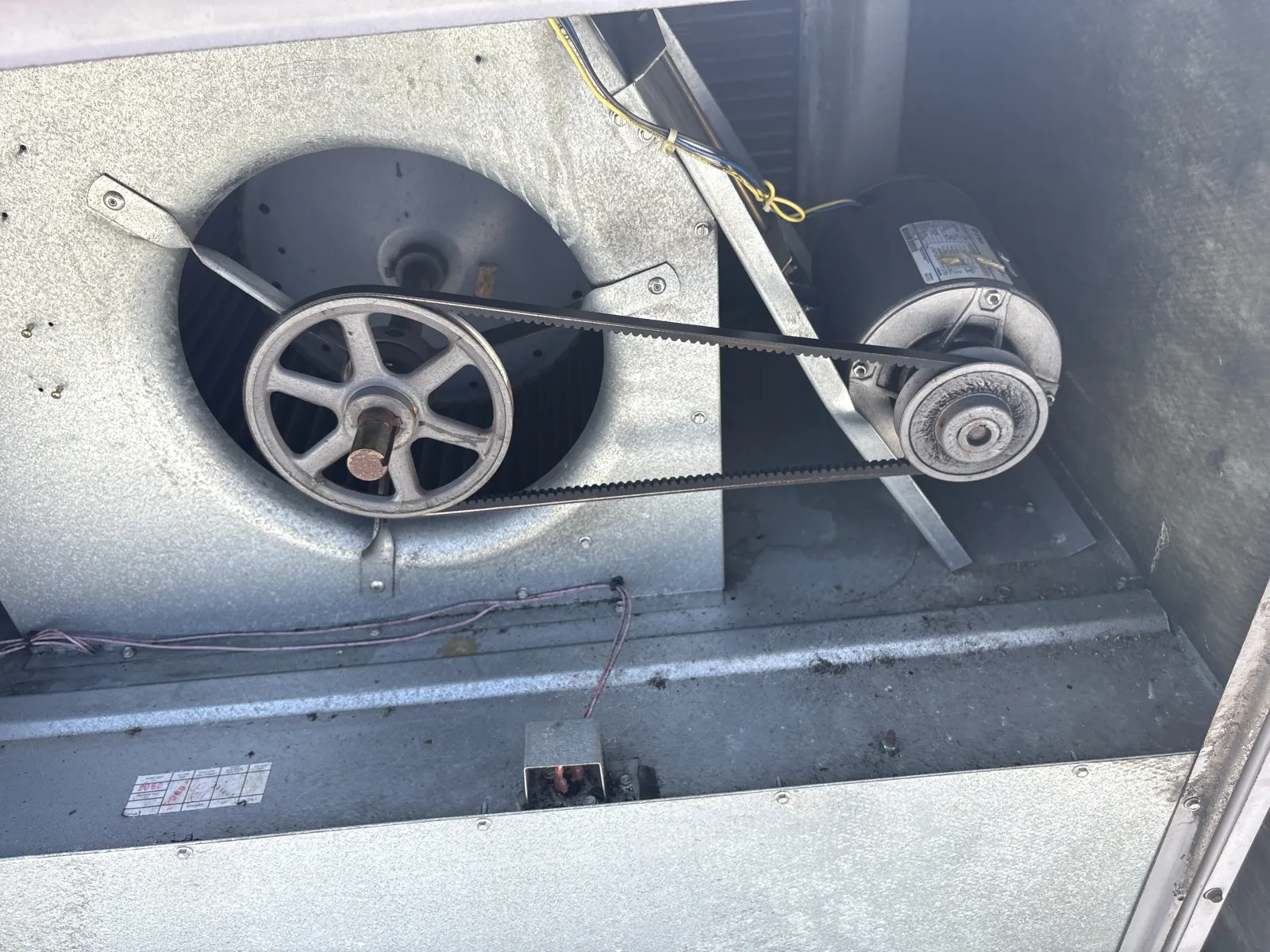 Metal HVAC blower fan system with motor and belt drive inside an industrial unit.