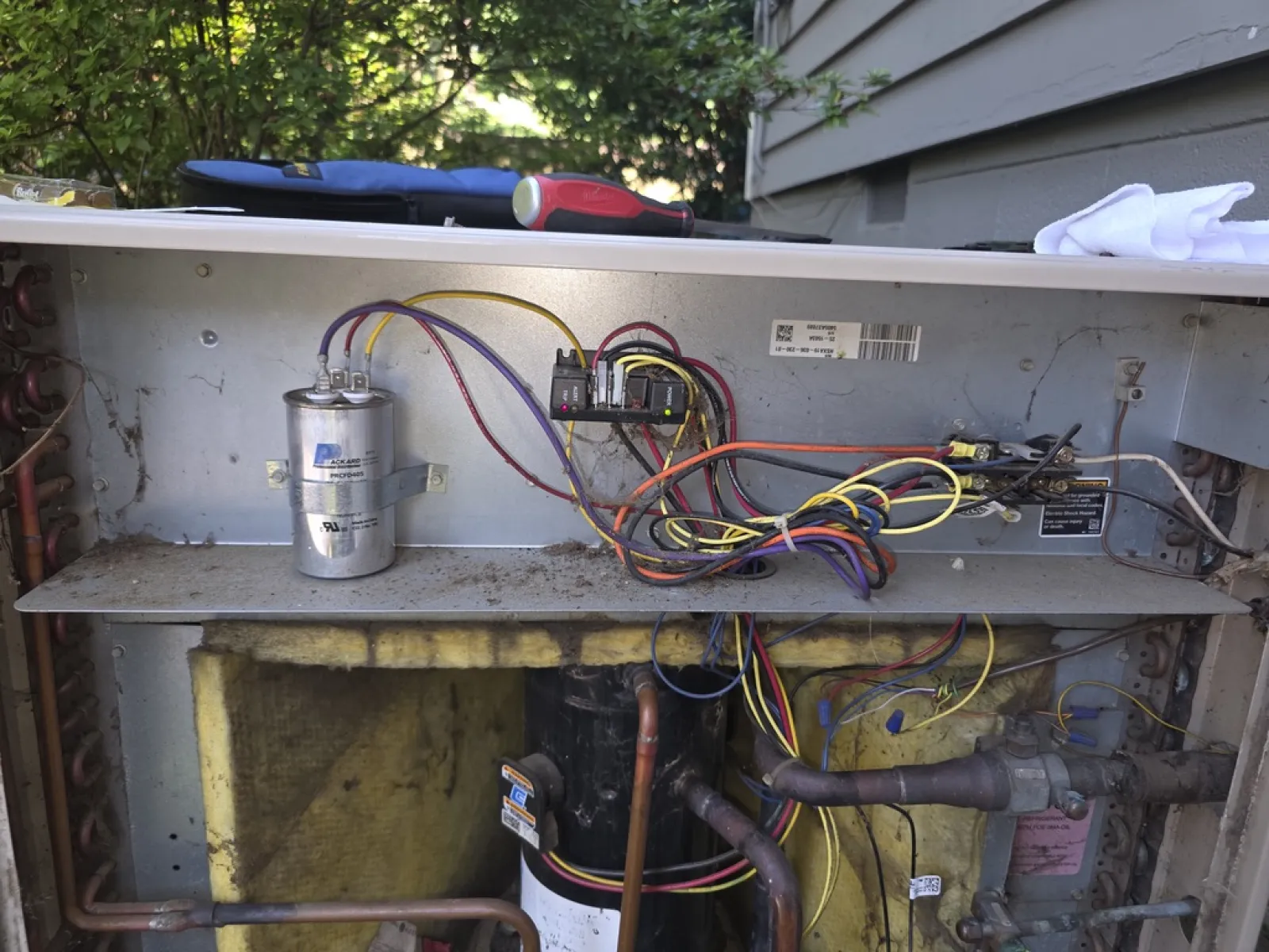 Exposed internal components and wiring of an HVAC unit with compressor and capacitors visible.